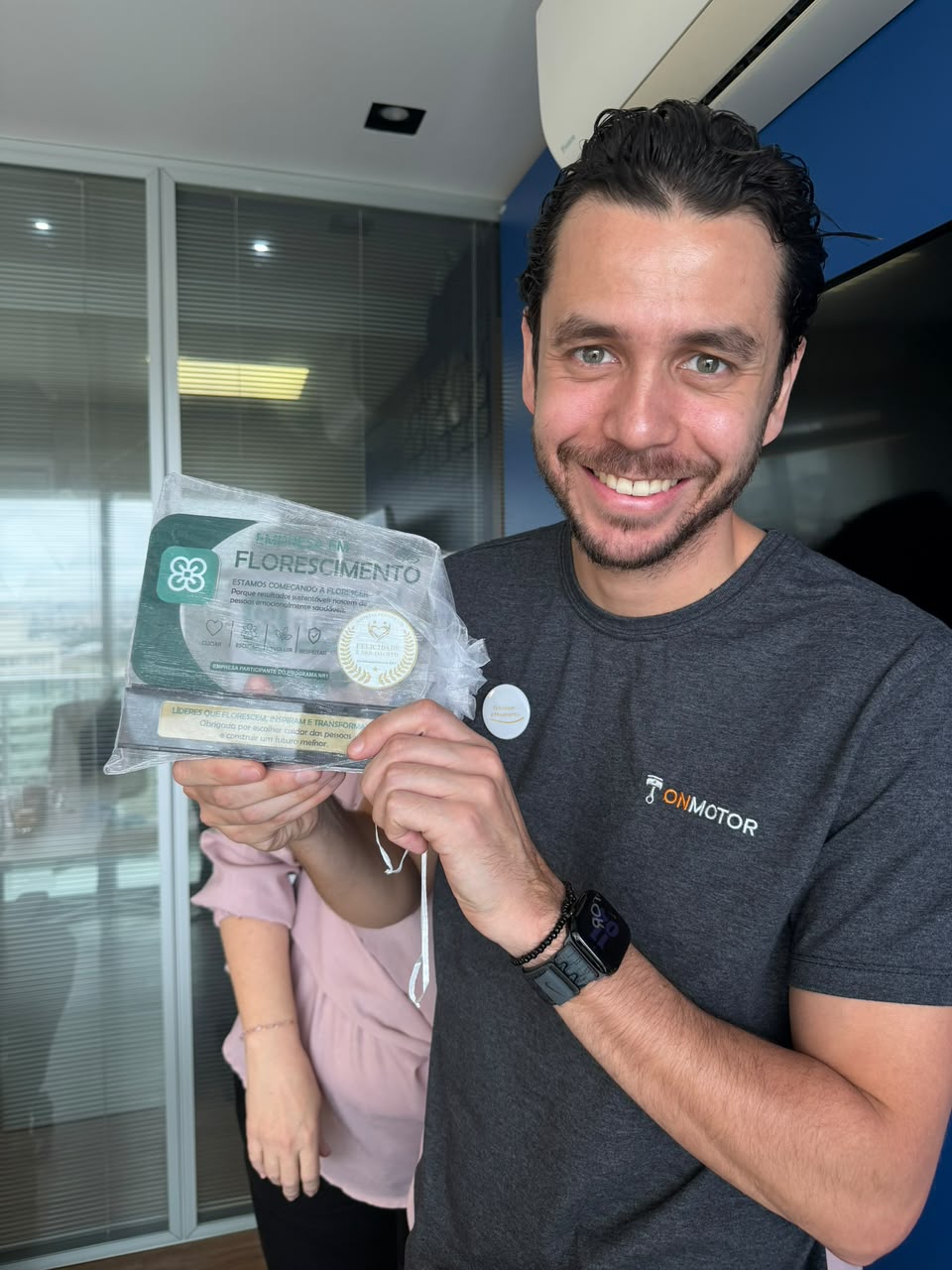 Participante do Programa Florescer NR-1 segurando o troféu Florescimento